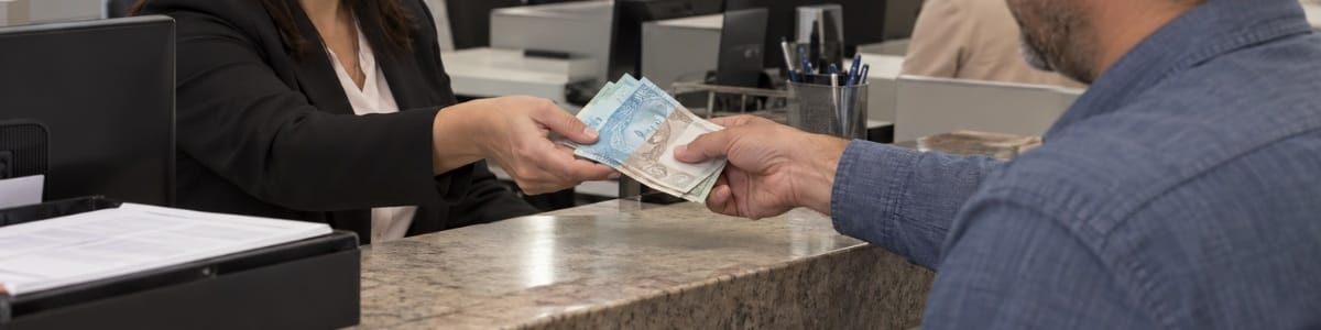 valor para unificar terrenos Pessoa realizando um pagamento em dinheiro a uma funcionária de cartório, em um ambiente institucional moderno e organizado